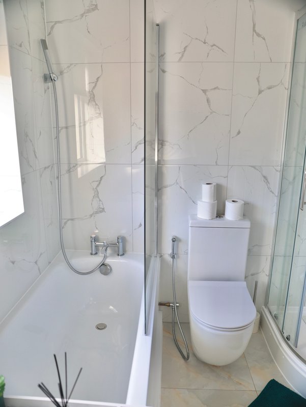 Modern bathroom with marble-effect tiles, walk-in shower, toilet and bath fixtures