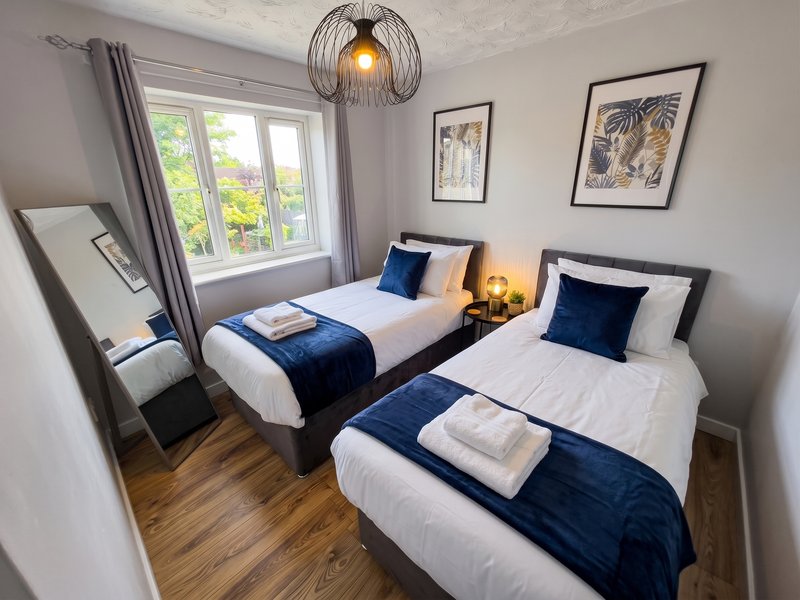 Twin bedroom with two single beds, blue throws, wooden floor and pendant light