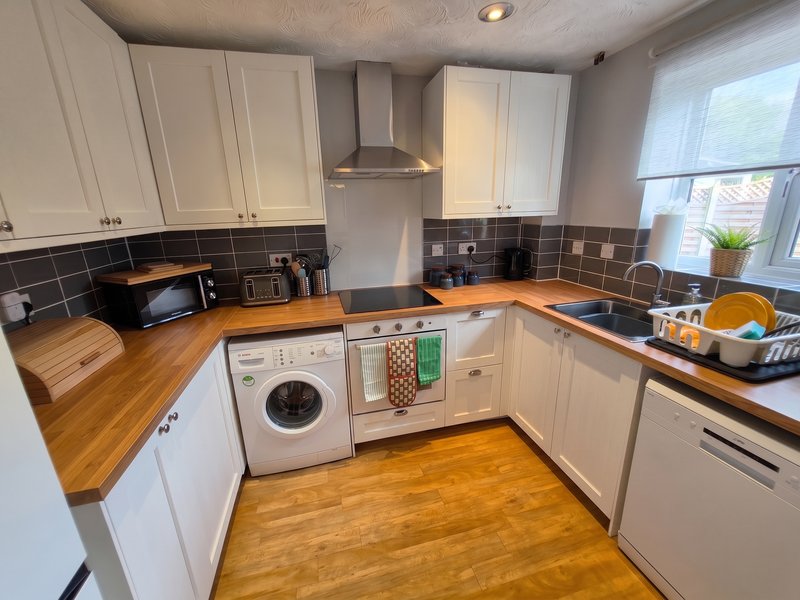 Modern kitchen with white cabinets, wooden countertops, integrated appliances and tile backsplash
