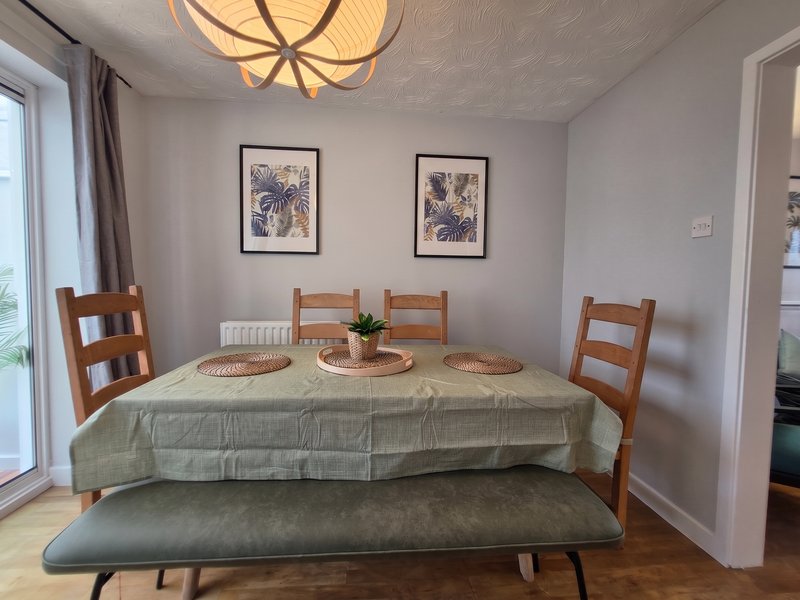 Dining room with wooden chairs, green tablecloth, framed artwork, and pendant ceiling light