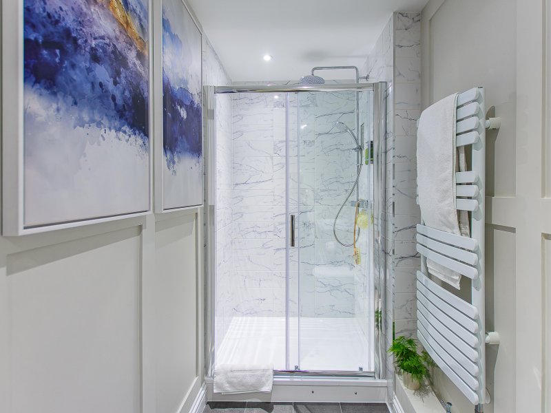 Modern bathroom with marble-effect shower enclosure, heated towel rail and abstract wall art