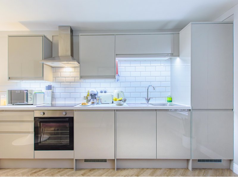 Modern kitchen with light gray cabinets, white subway tile backsplash, stainless steel appliances and countertop