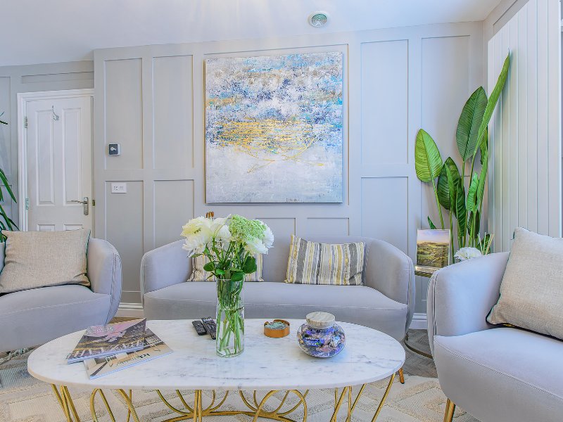 Bright living room with grey seating, marble coffee table, fresh flowers, and abstract artwork