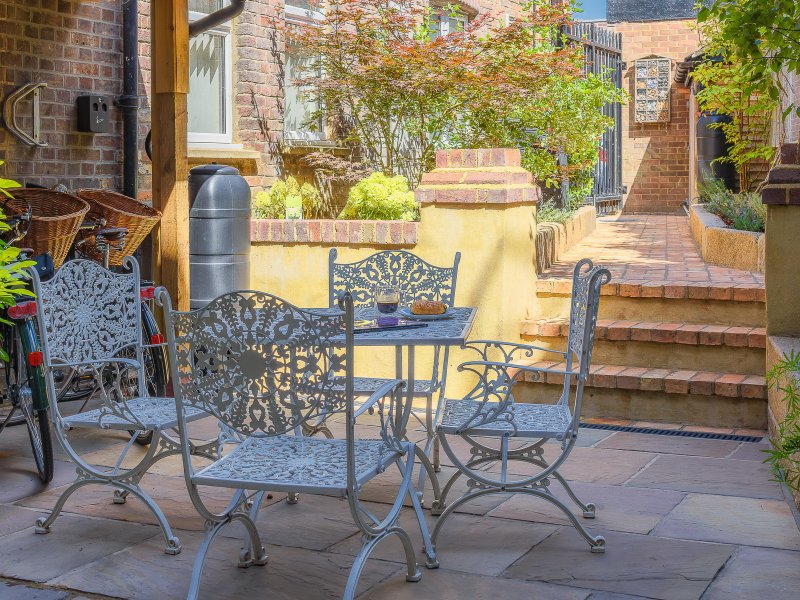 Outdoor patio with cast-iron garden furniture, brick walls, and climbing ivy