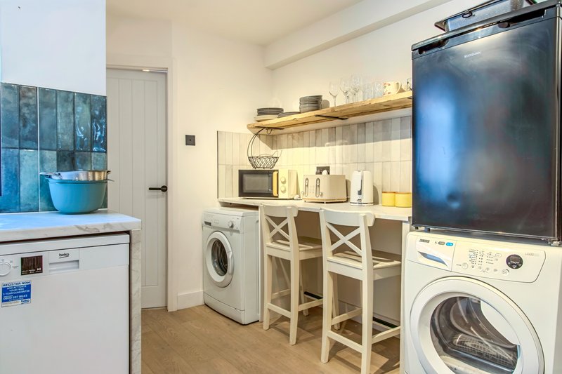 Utility room with washing machine, dryer, kitchen counter, microwave and bar seating