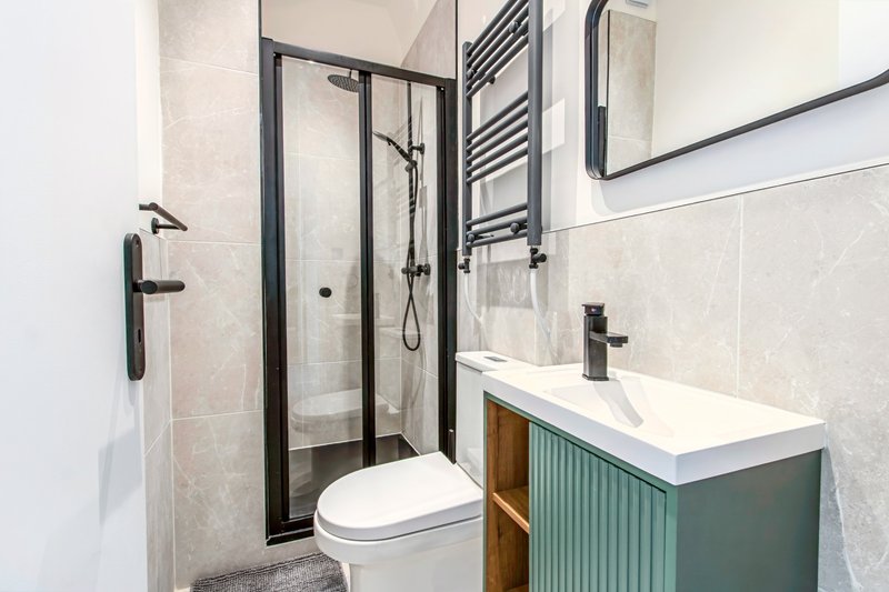 Modern bathroom with shower enclosure, toilet, vanity sink and heated towel rail