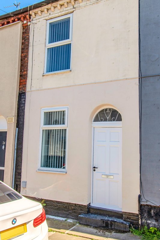 Cream-coloured terraced house exterior with white door, blue-framed windows and brick side wall