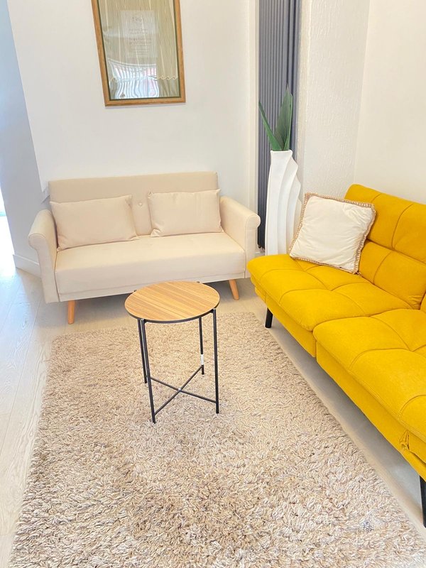 Modern living room with cream sofa, yellow sofa, wooden side table and potted plant