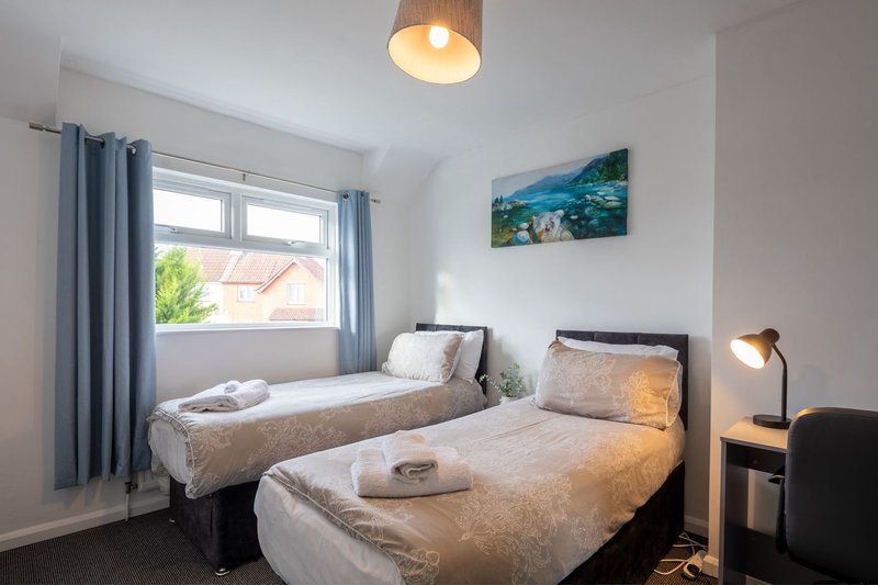 Twin bedroom with two single beds, blue curtains, ceiling lamp and bedside lighting