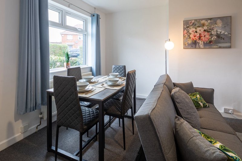 Open-plan living and dining area with sofa, dining table, chairs, and window with curtains