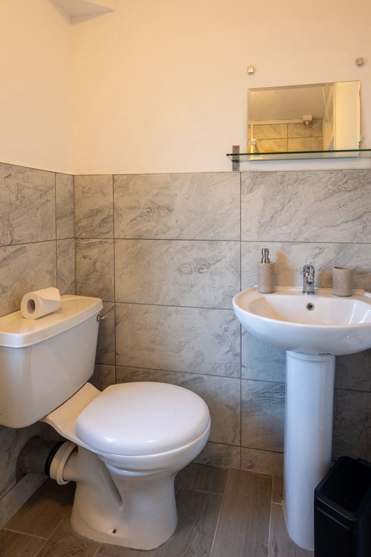 Small bathroom with toilet, pedestal sink, marble tile walls and mirror cabinet