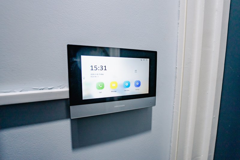 Wall-mounted digital display screen showing time and app icons in modern home
