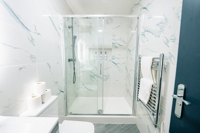 Modern bathroom with walk-in shower, marble-effect tiling, white fixtures and heated towel rail
