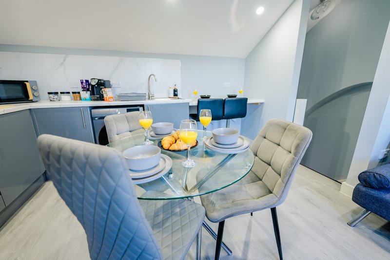 Modern kitchen-diner with glass table, quilted chairs, place settings and yellow fruit centerpiece
