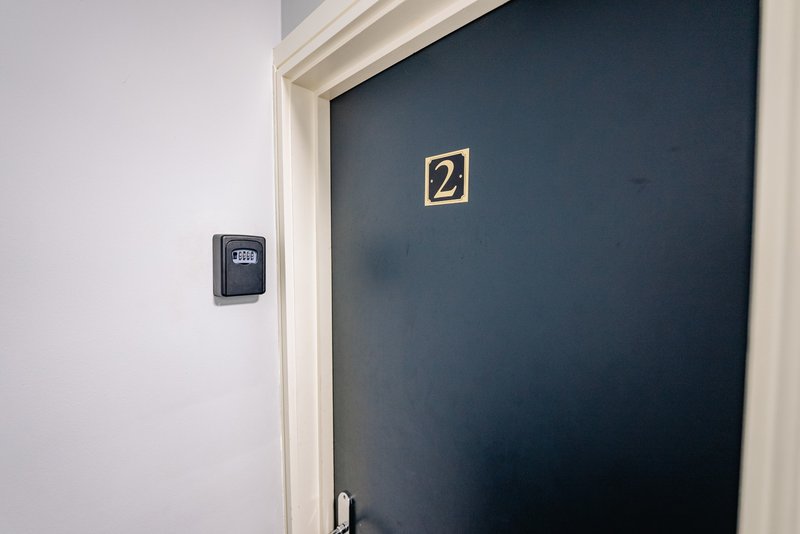 Dark blue apartment door with gold number 2 plaque and digital keypad