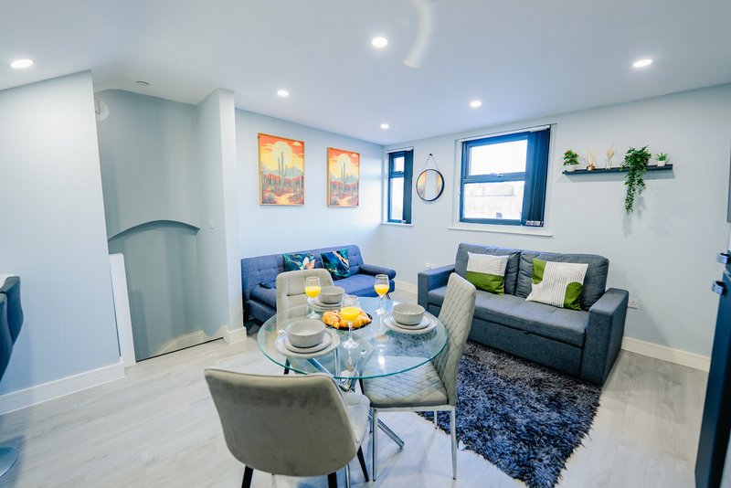 Modern open-plan living and dining area with blue sofa, dining table, and armchairs