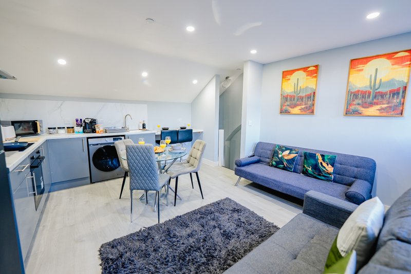Open-plan kitchen and living area with blue sofa, dining table, and modern appliances
