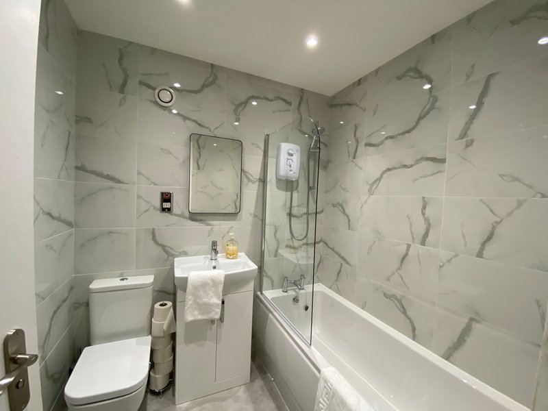 Modern bathroom with marble-effect tiles, white suite, shower enclosure and vanity sink