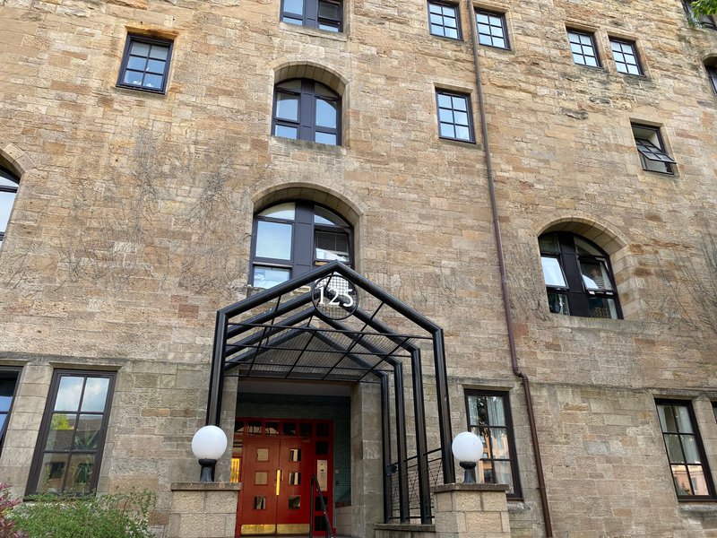 Stone building exterior with red entrance door, black metal canopy, and multiple windows