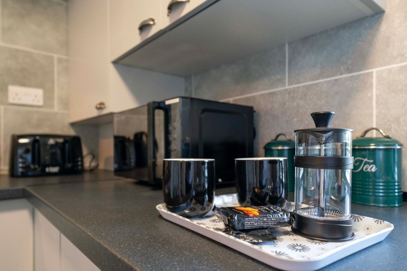 Modern kitchen counter with kettle, coffee maker, tea canister and appliances
