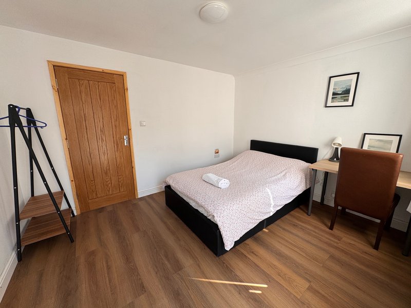 Bedroom with double bed, wooden door, bedside table, wooden floor and wall art