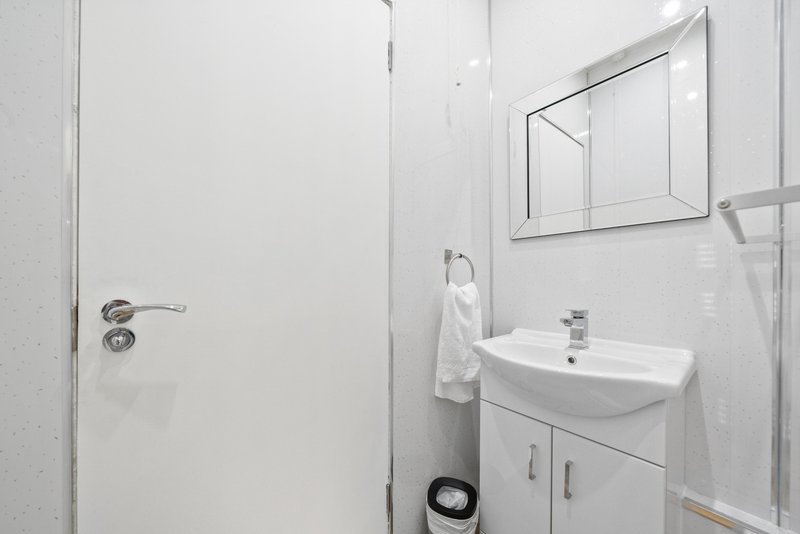Clean modern bathroom with white vanity, mirror, towel rail and shower enclosure