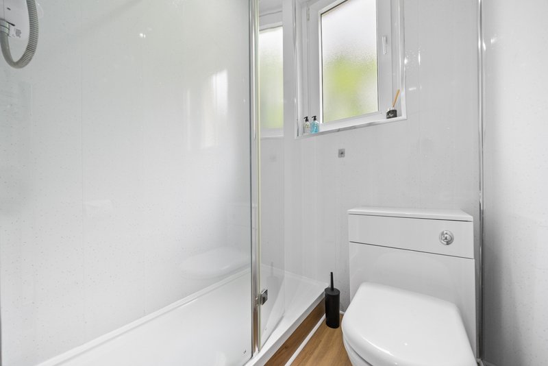 Compact bathroom with toilet, sink, shower enclosure and window
