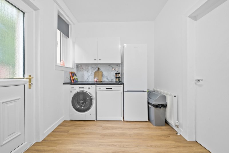 Modern utility room with washing machine, dryer, white cabinetry, wooden floor and window