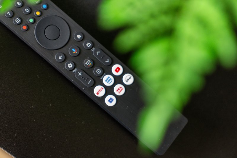 Close-up of a black television remote control with colored buttons and directional pad