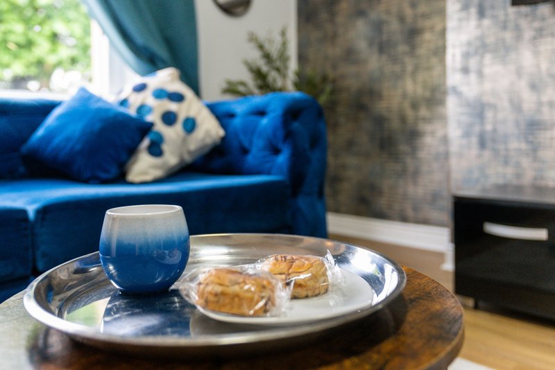 Living room with blue sofa, coffee table with cup and pastries, cushions and curtains