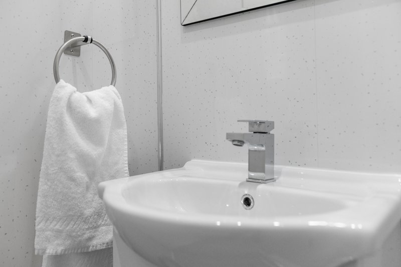 Modern bathroom with white pedestal sink, chrome faucet, and towel ring with hanging towel