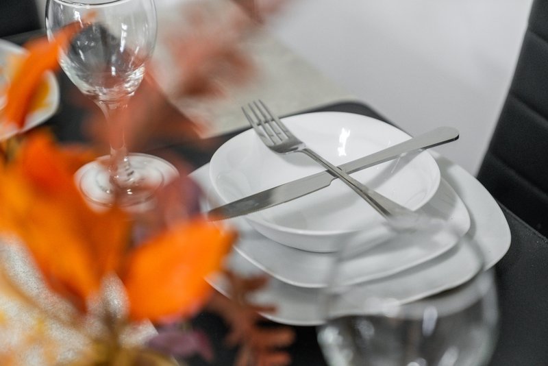 Formal table setting with white plates, wine glass, and orange flowers