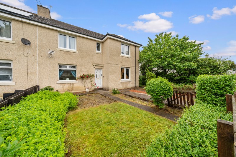 Cream-coloured semi-detached house with garden, lawn, hedges and wooden fence