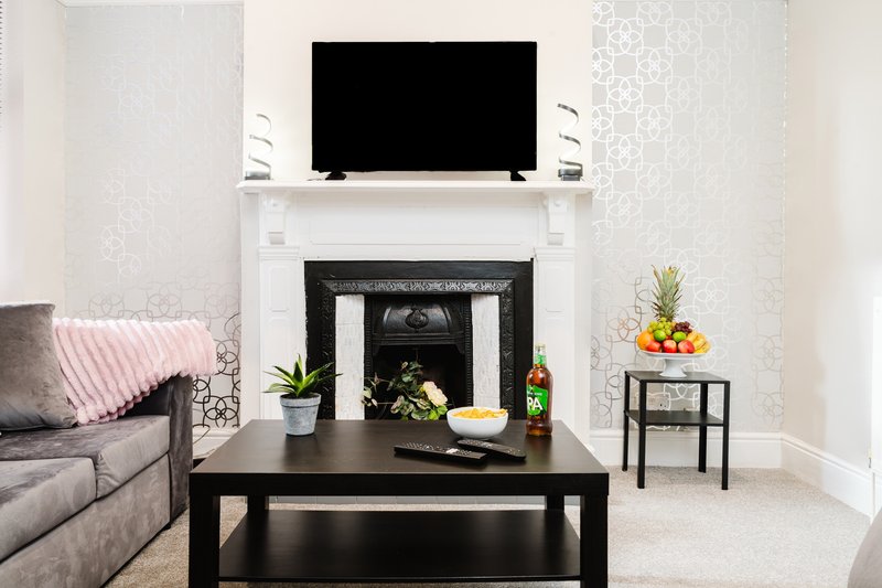 Living room with fireplace, wall-mounted TV, black coffee table and grey sofa