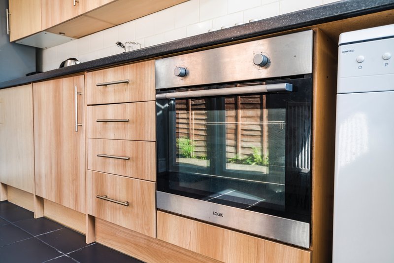 Modern kitchen with wooden cabinets, stainless steel oven, and dark countertop