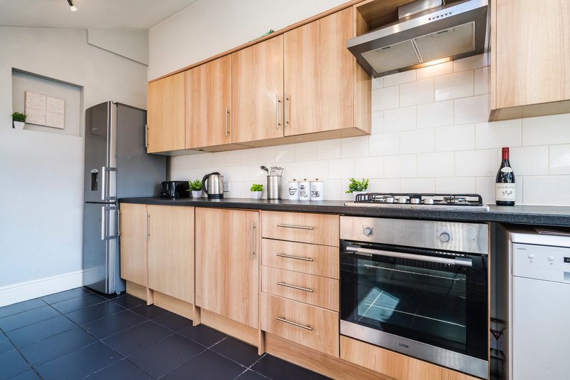 Modern kitchen with wooden cabinets, stainless steel appliances, black countertop and white subway tiles