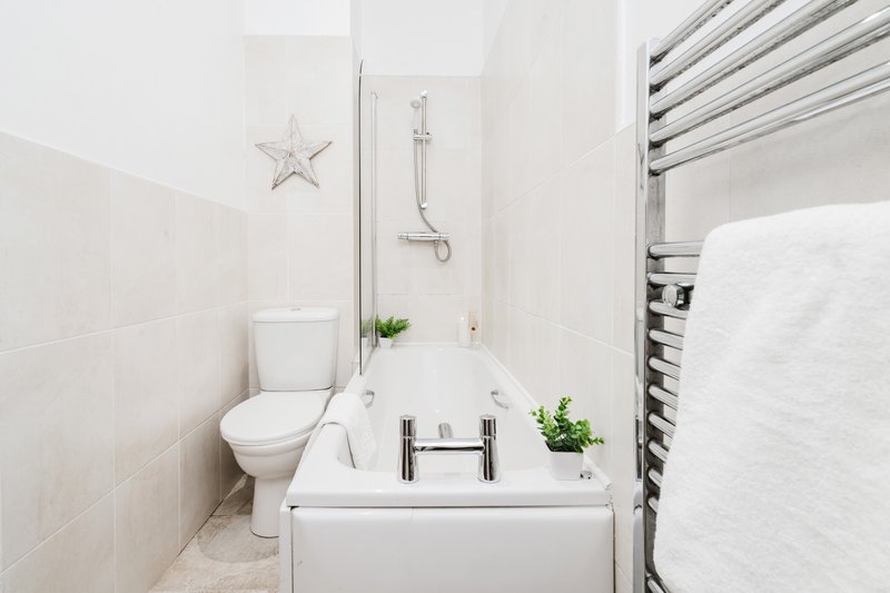 Clean white bathroom with toilet, sink, shower, towel rail and decorative star