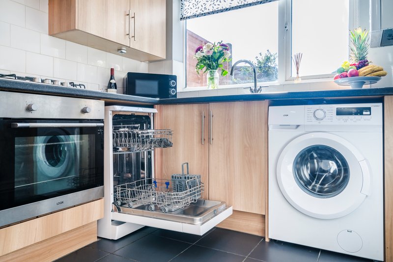 Modern kitchen with wooden cabinets, integrated appliances, dishwasher, and blue countertop