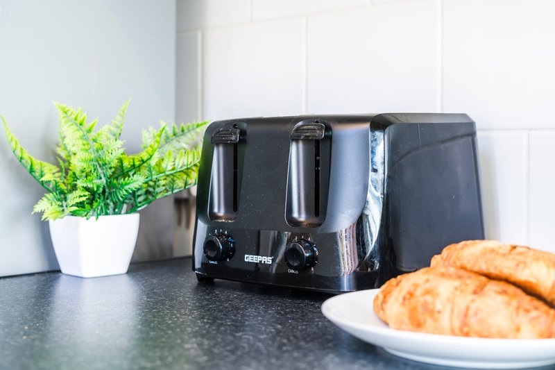Kitchen counter with black toaster, white potted plant, and plate of pastries
