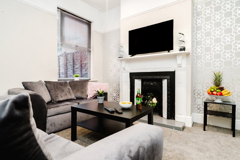 Modern living room with grey sofas, fireplace, TV, coffee table and decorative plants