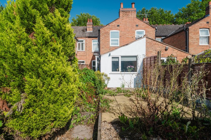 Brick terraced house with white extension, garden and green hedging