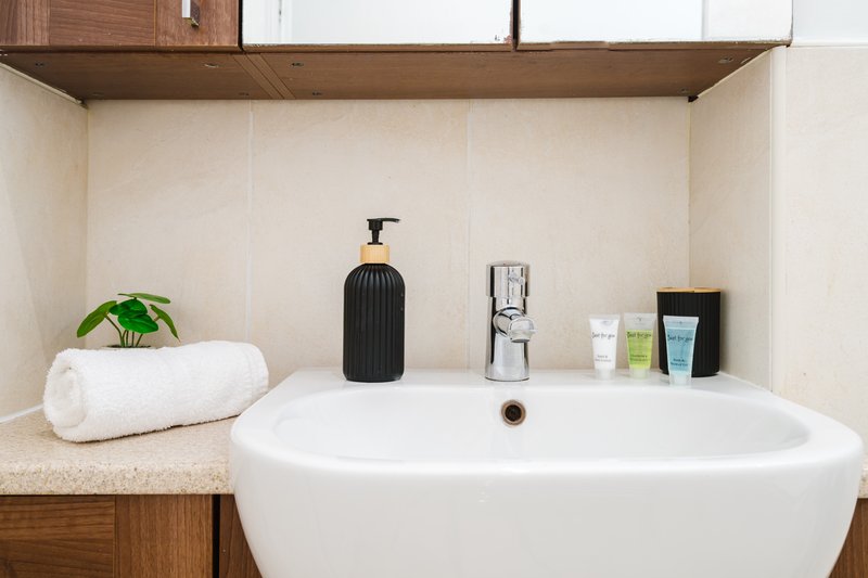 Modern bathroom with white freestanding tub, wooden vanity, toiletries and towels