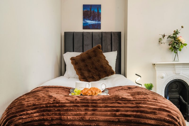 Bedroom with brown velvet bed, grey headboard, white pillows and decorative cushion