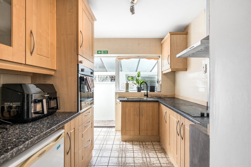 Modern galley kitchen with wooden cabinets, granite countertops, and view to garden