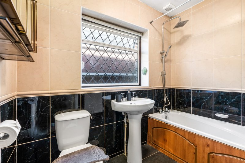 Bathroom with pedestal sink, toilet, bathtub and black tile wainscoting