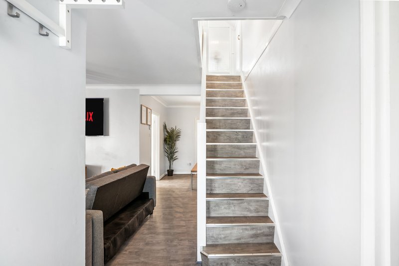 Modern hallway with staircase, brown sofa, and potted plant