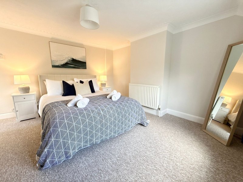 Spacious bedroom with double bed, neutral decor, bedside lamps and full-length mirror