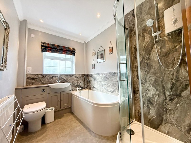 Modern bathroom with curved freestanding tub, separate walk-in shower, and vanity with window
