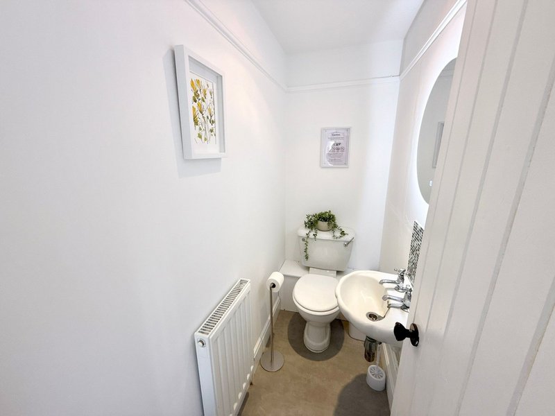 Small bathroom with toilet, sink, radiator and framed wall art
