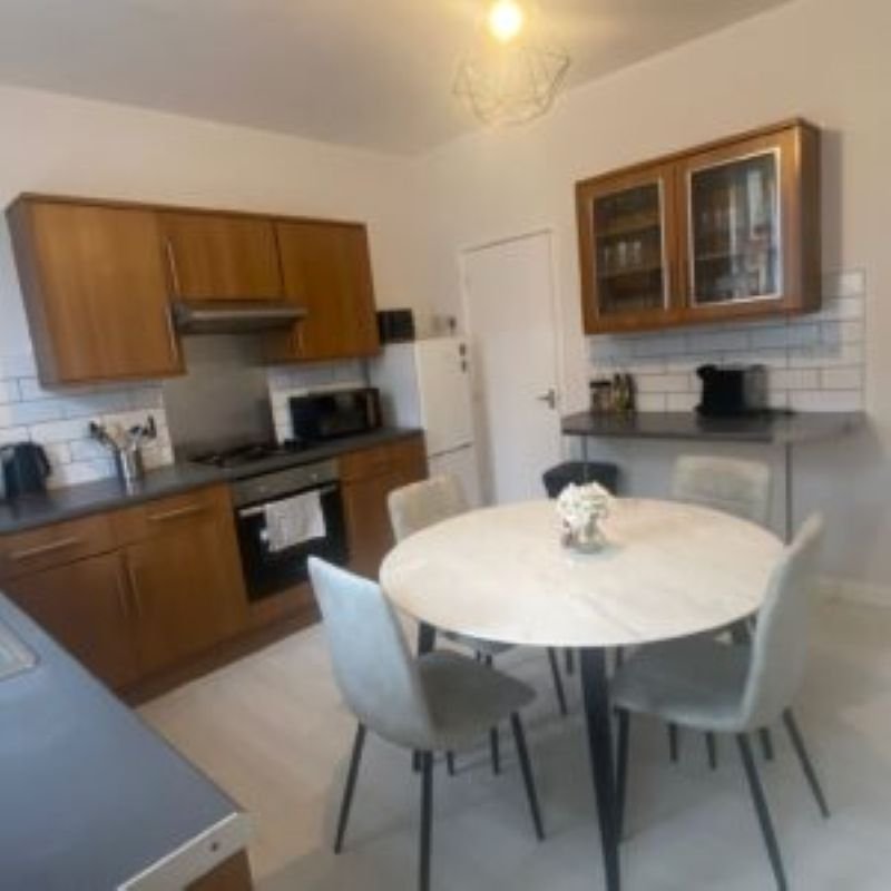 Modern kitchen-diner with wooden cabinets, round white table, and dining chairs